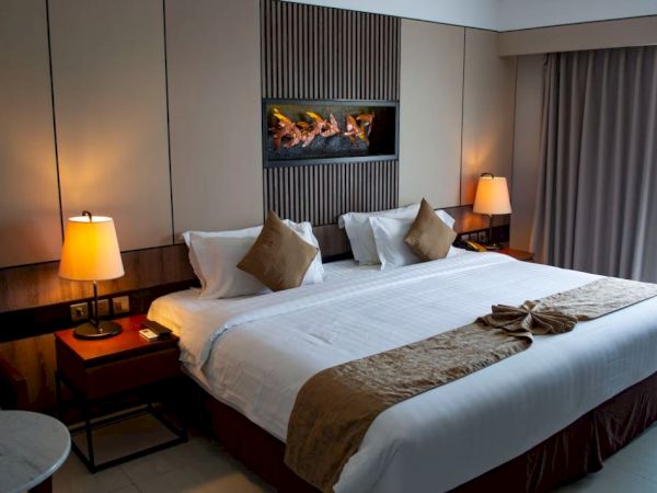 A cozy hotel room with a large bed, decorative pillows, side tables with lamps, and curtains, creating a welcoming atmosphere.